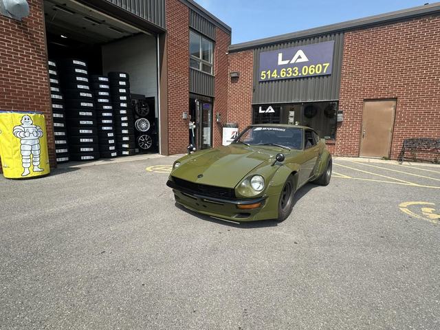 Tires and wheels stacked in the garage's open bay, with a green sports car parked out front.